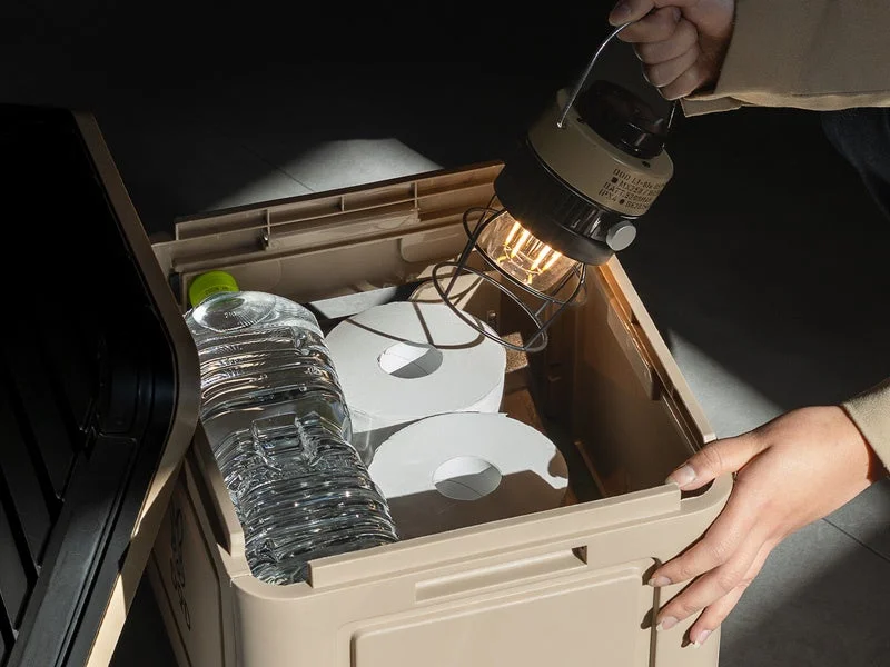 人物が点灯したランタンをベージュの収納ボックスに入れている様子