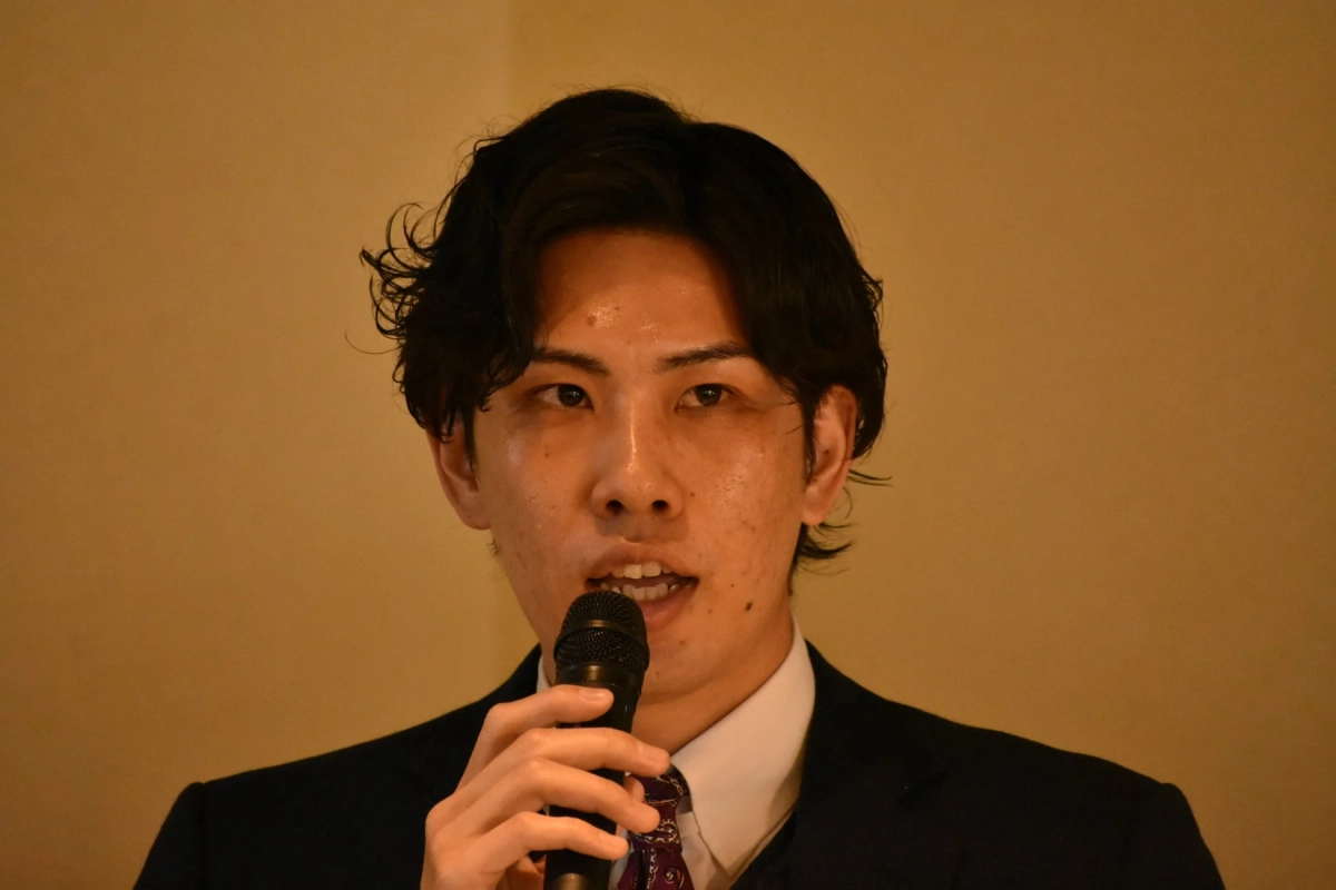 マイクを持って話す男性