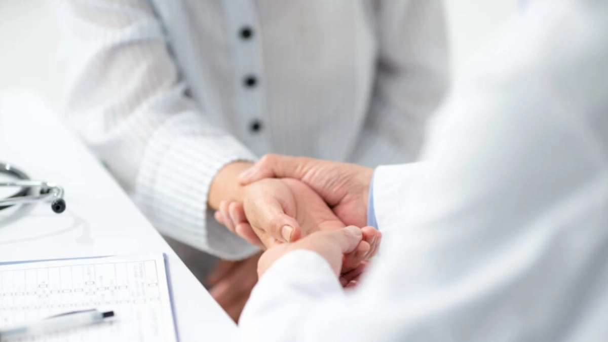 医師が患者の手を優しく握っている様子