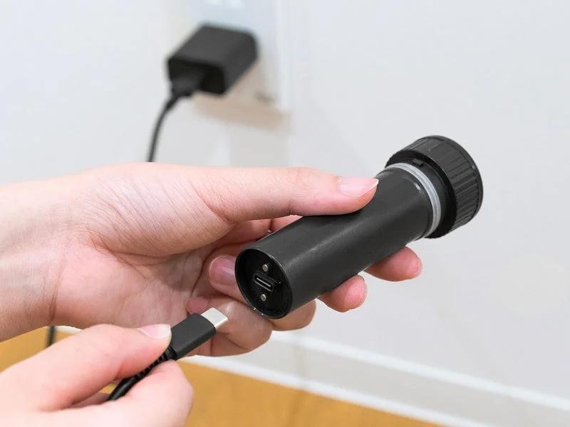 人物が黒い筒状のデバイス（懐中電灯のよう）にUSB-Cケーブルを差し込もうとしている