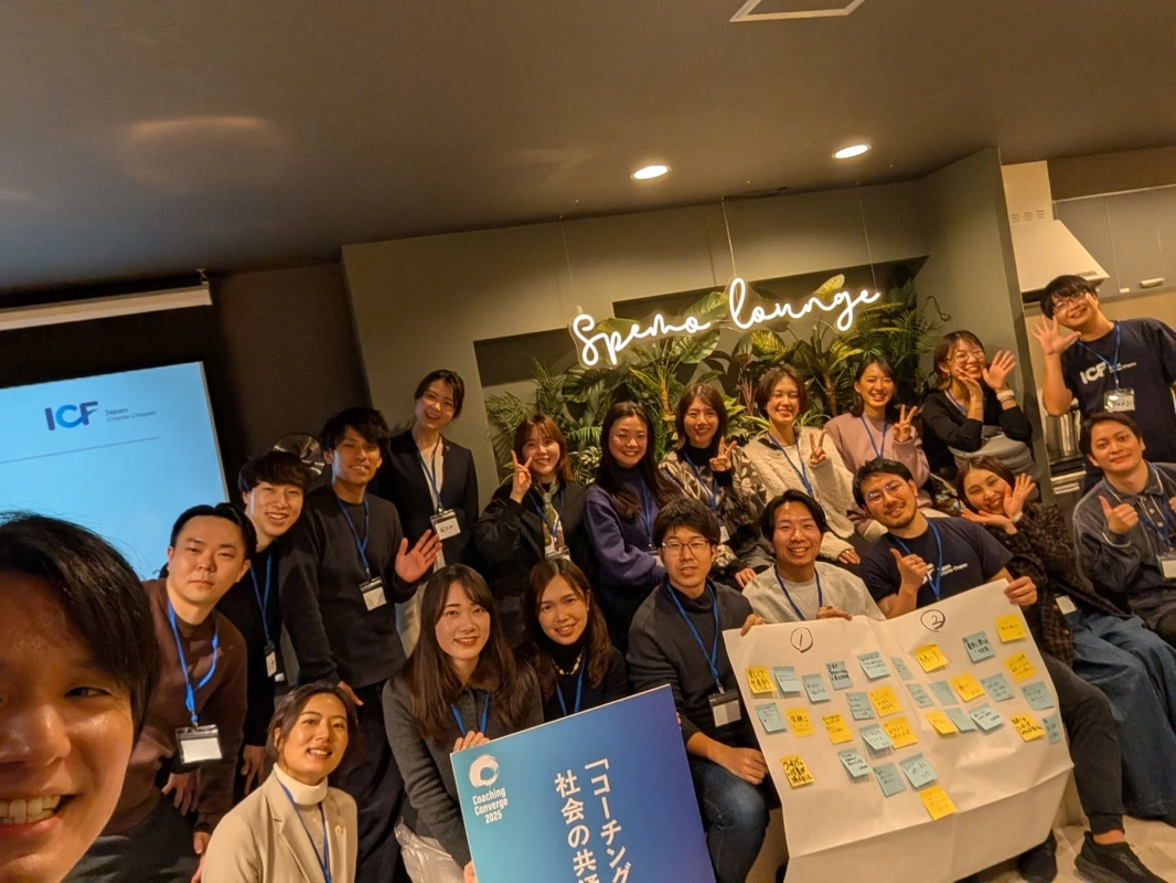 屋内スペースで、多くの若者が笑顔で集合写真を撮っています