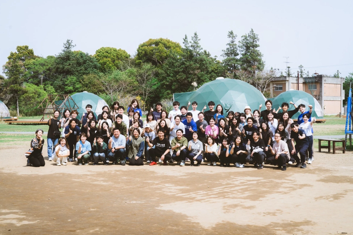 屋外で笑顔でサムズアップポーズをとる人々