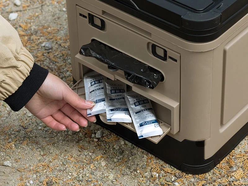 屋外で、人がベージュと黒の携帯用容器から「凝固剤」と書かれた小袋を取り出している様子