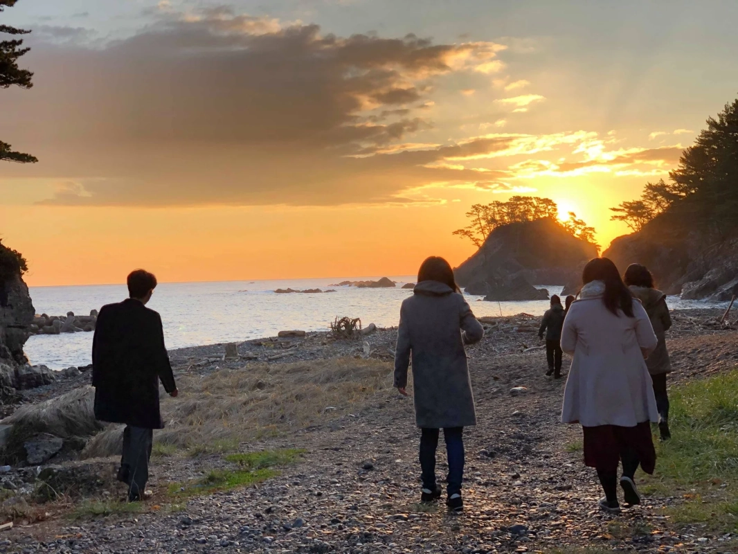 夕焼けの海岸を歩く人々