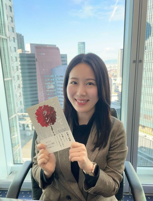 書籍を手に笑顔を見せる岡田光莉氏