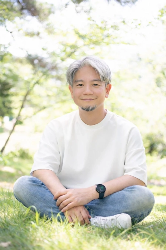 公園の芝生に座って微笑む男性