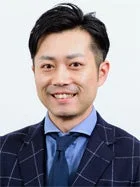 ビジネススーツを着用したアジア系の男性が、カメラに向かって笑顔で写っているポートレート写真です。真面目な印象ですが、親しみやすさを感じさせます。