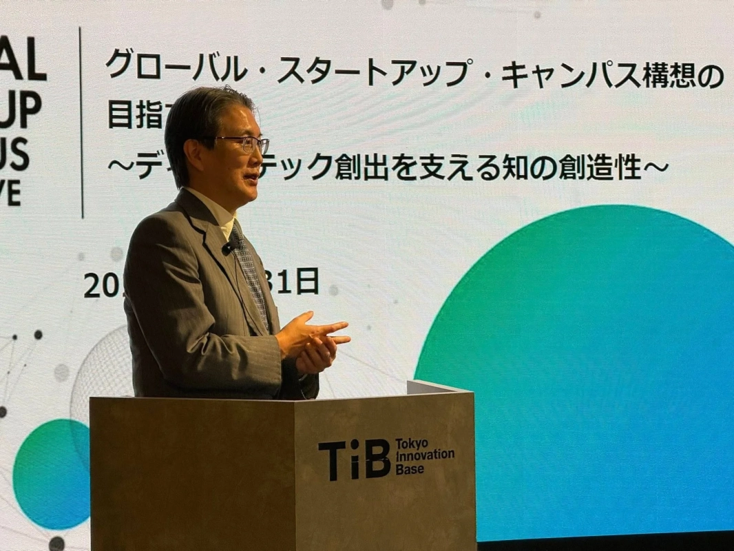 東京イノベーションベースのイベントで、スーツ姿の男性が「グローバル・スタートアップ・キャンパス構想」をテーマに講演中