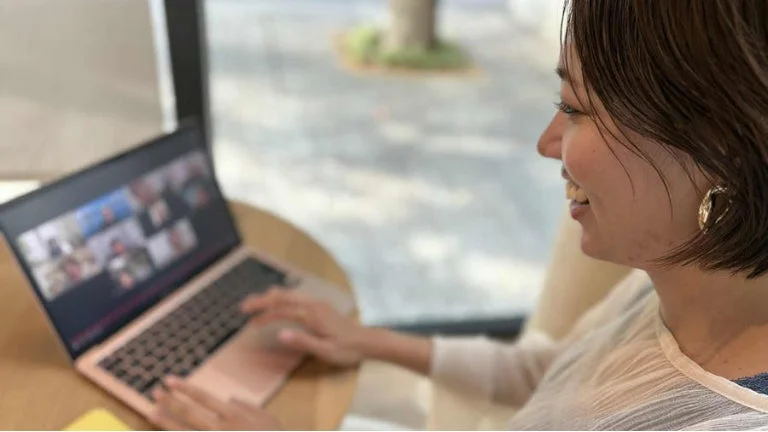 ノートパソコンでオンライン会議に参加している笑顔の女性