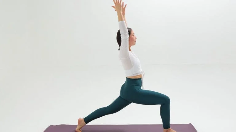 ヨガマットの上でウォーリアーIのポーズをとる女性